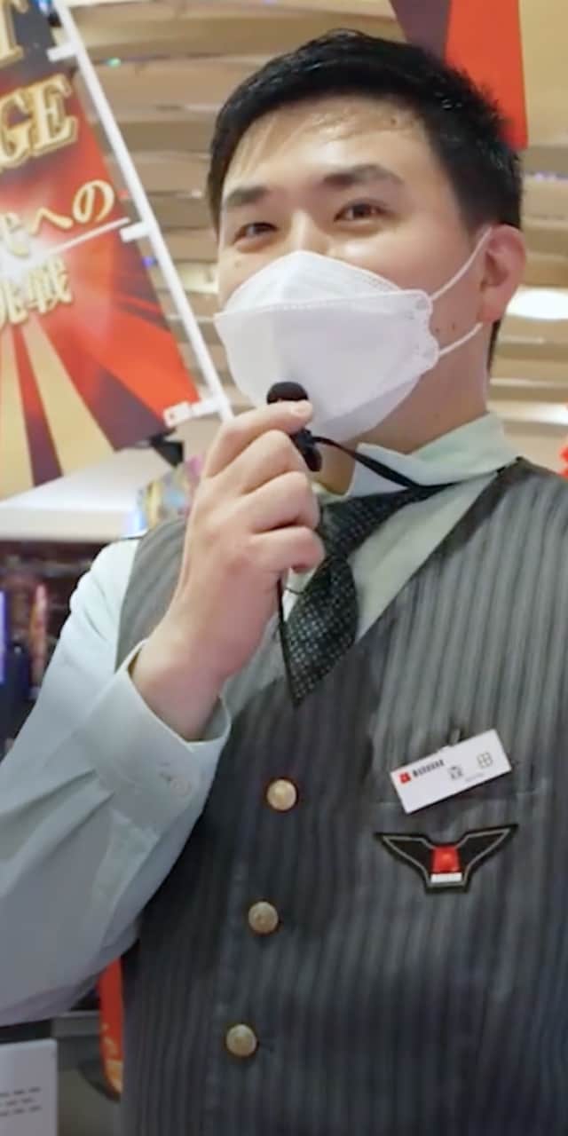 カジュアルな制服を着た男性がマイクを持ち、話しかけている様子が印象的。